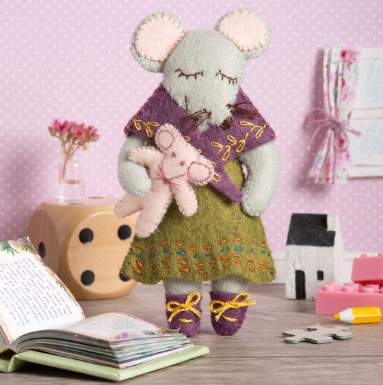 Corinne Lapierre Felt Craft Mini Kit. A mouse character is stood wearing a green dress and purple shawl and shoes. She is holding a pale pink teddy.. 