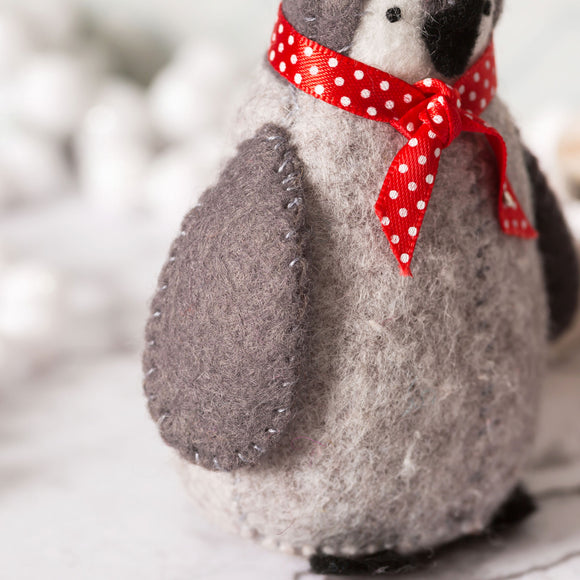 Corinne Lapierre Felt Baby Penguins Craft Kit. Snow Scene. 3 felt penguins in grey, black & white, with red ribbon tied at neck.