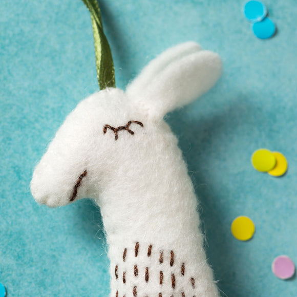 Corinne Lapierre Llama Felt Craft Kit. white llama with colourful saddle, hung with green ribbon.