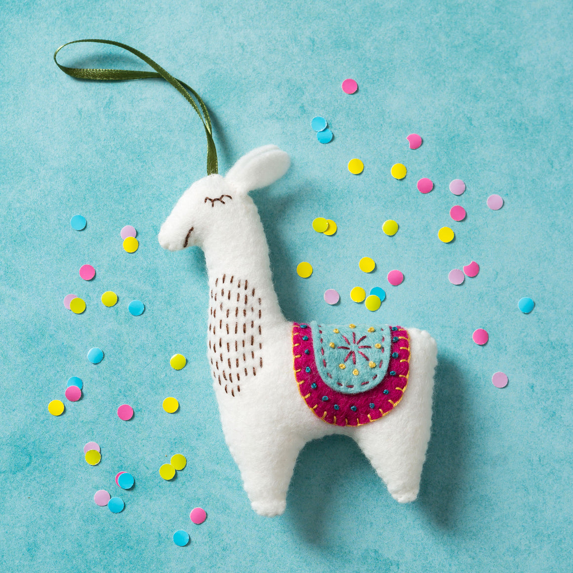 Corinne Lapierre Llama Felt Craft Kit. white llama with colourful saddle, hung with green ribbon.